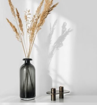 a black vase with some dry grass in it